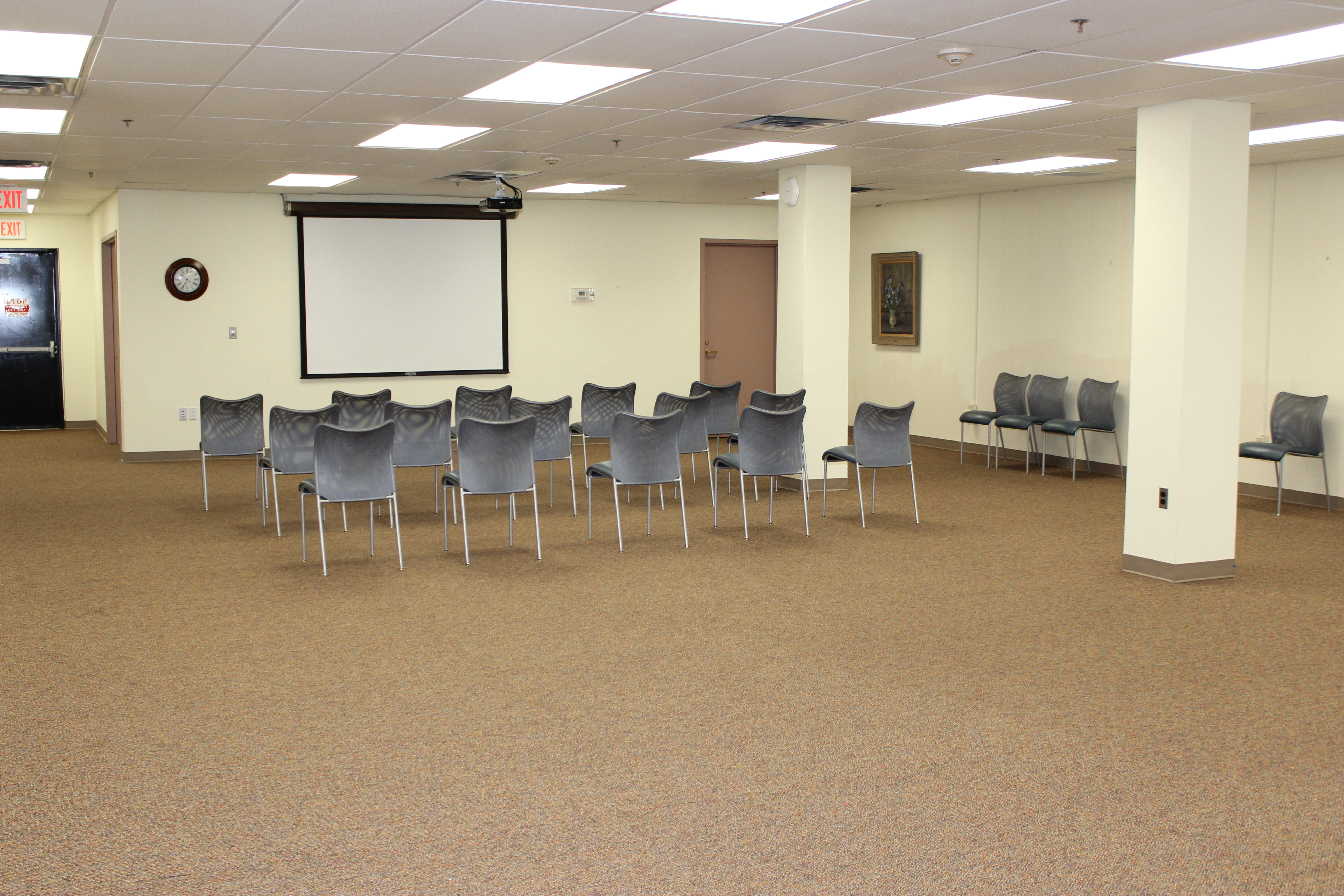 Meeting room with chairs. Projector screen on wall.