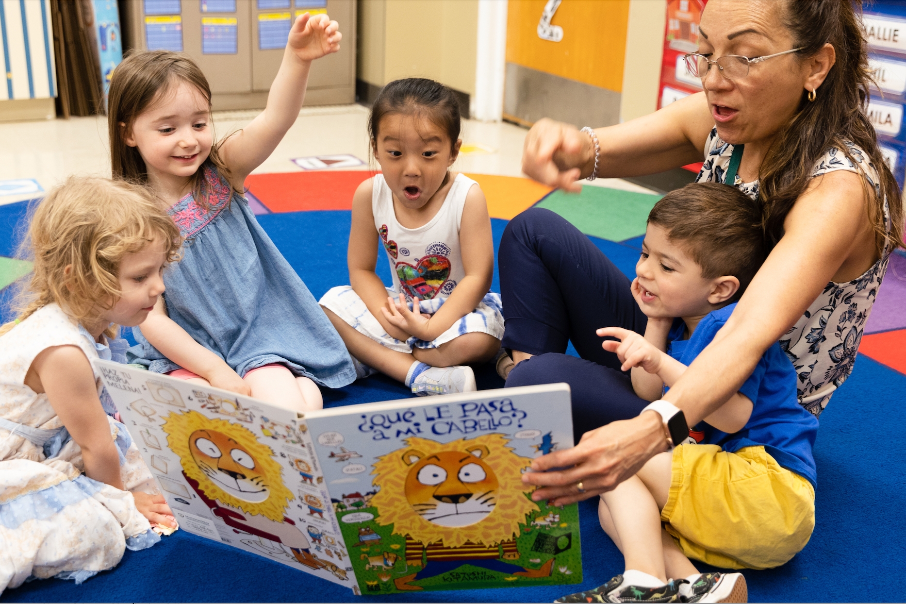 female teacher reading to happy children