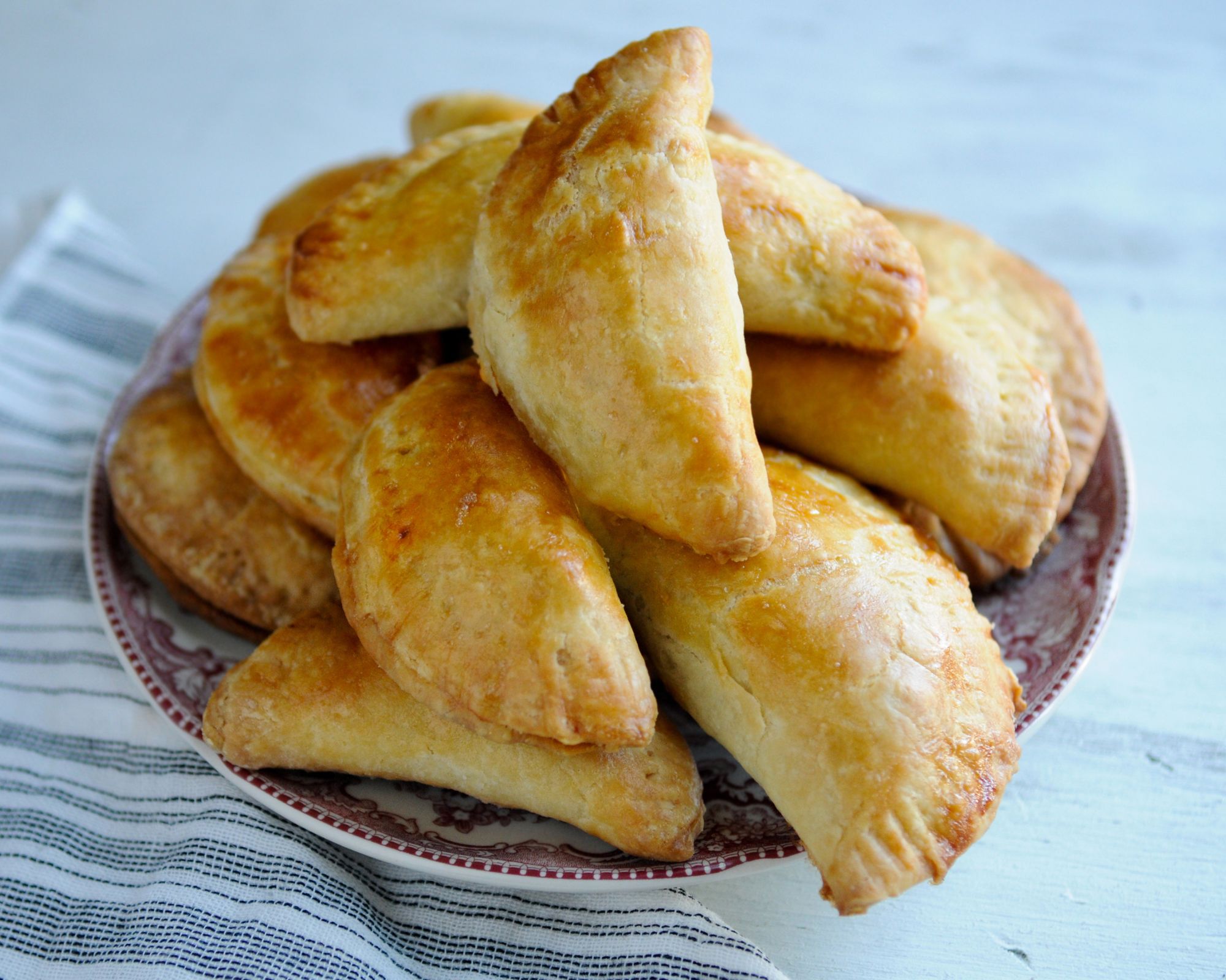 baked empanadas stacked on a plate