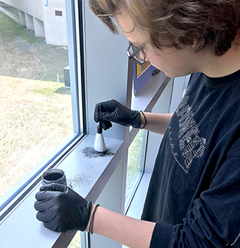 Young student wearing gloves and using fingerprinting dust