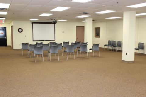 Meeting room with chairs. Projector screen on wall.