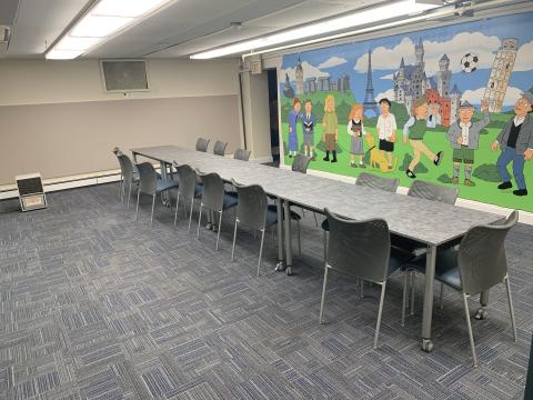 Meeting room with tables and chairs. There is a mural on the wall.
