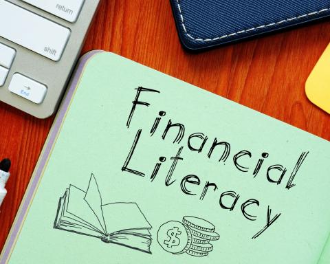 the words "financial literacy" written in notebook with a drawing of an open book and coins