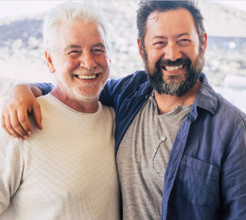 two older men standing next to each other smiling