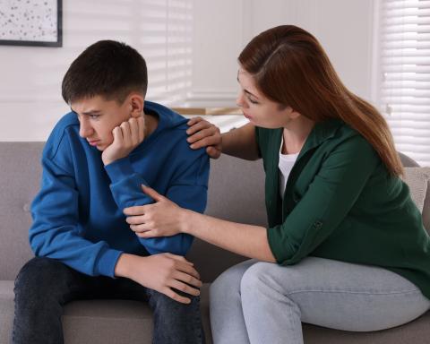 adult consoling teenager on a couch