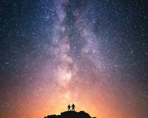 image of two people looking at the colorful universe of stars