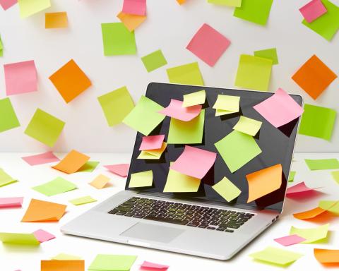 image of an open laptop with multicolored sticky notes on and around it