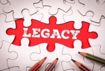 white puzzle pieces around a red puzzle piece reading "legacy" with 4 pencils on top of puzzle