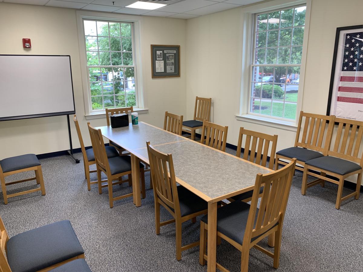 Meeting room with tables and chairs. White board in background.