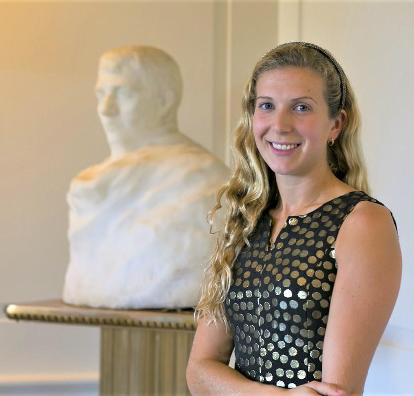 smiling woman standing next to a sculpture