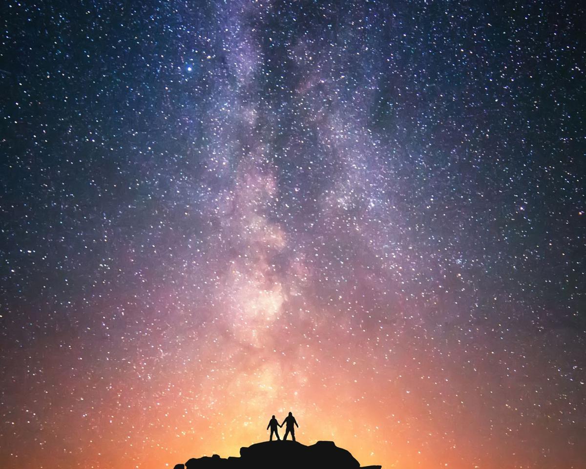 image of two people looking at the colorful universe of stars