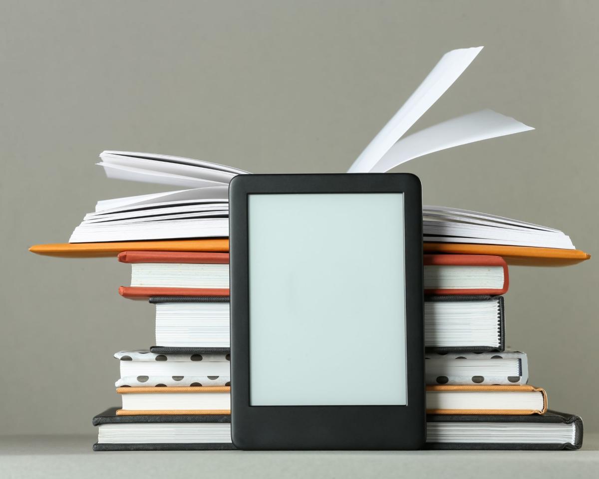 image of an e-reader in front of a stack of books