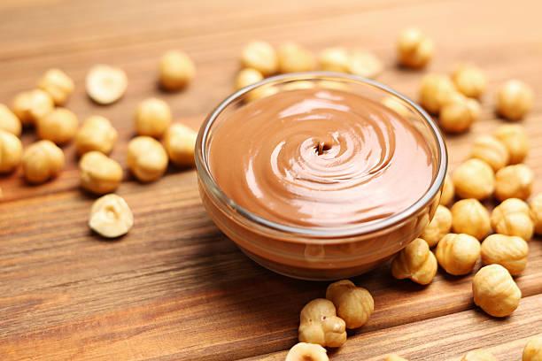Bowl of Nutella surrounded by hazelnuts